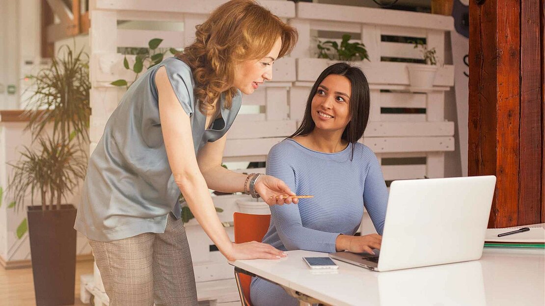Foto: Frau spricht mit junger Frau am Laptop - Praktikum 