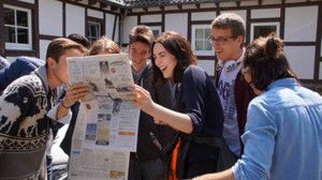 Foto: junge Menschen schauen in die Zeitung